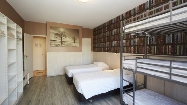 Quarto com beliches, estante de livros e um quadro na parede.