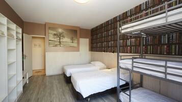 Een kamer met stapelbedden, een boekenkast en een schilderij aan de muur.