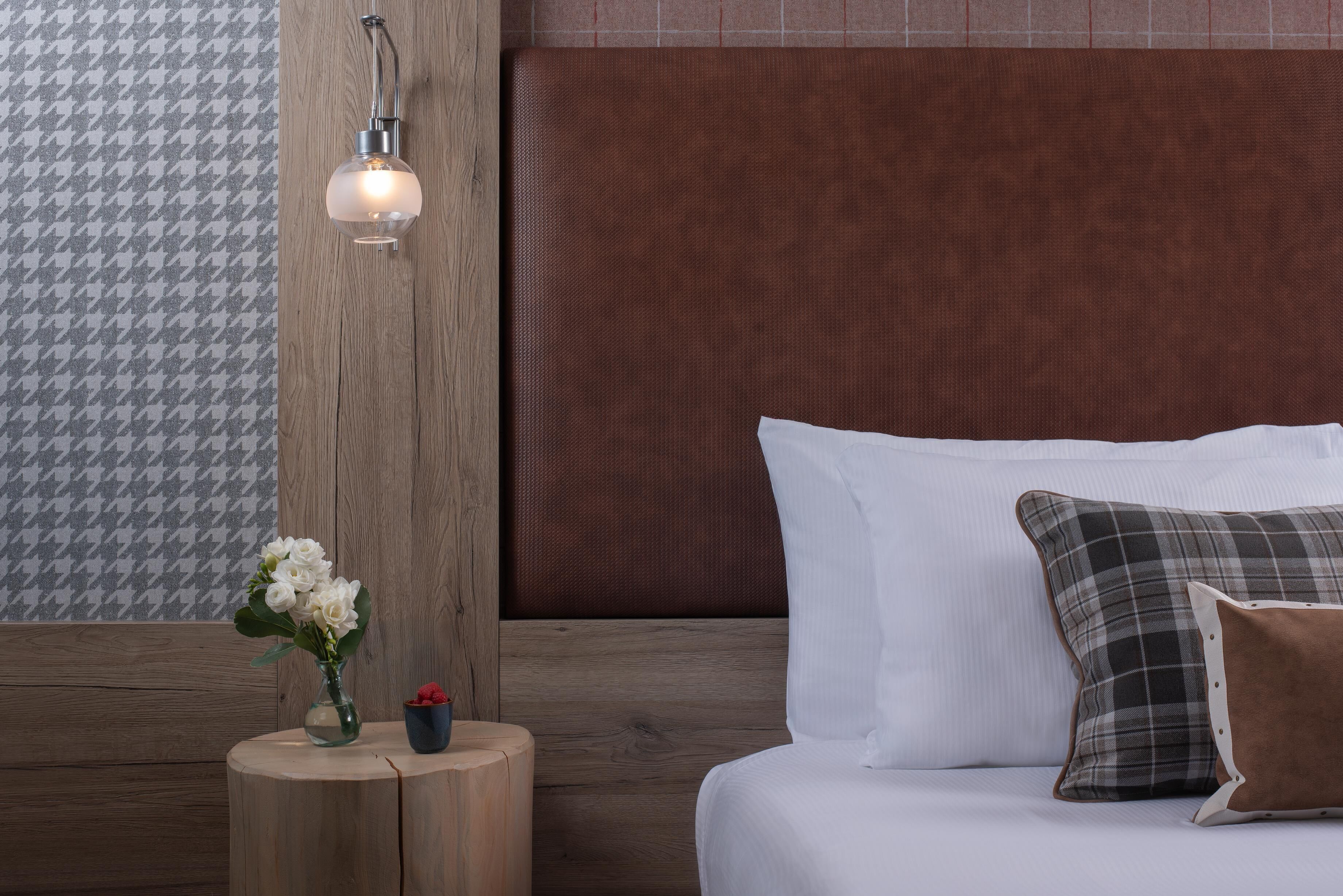 Una camera da letto con una testiera in legno, un comodino con un vaso di fiori e una lampada.