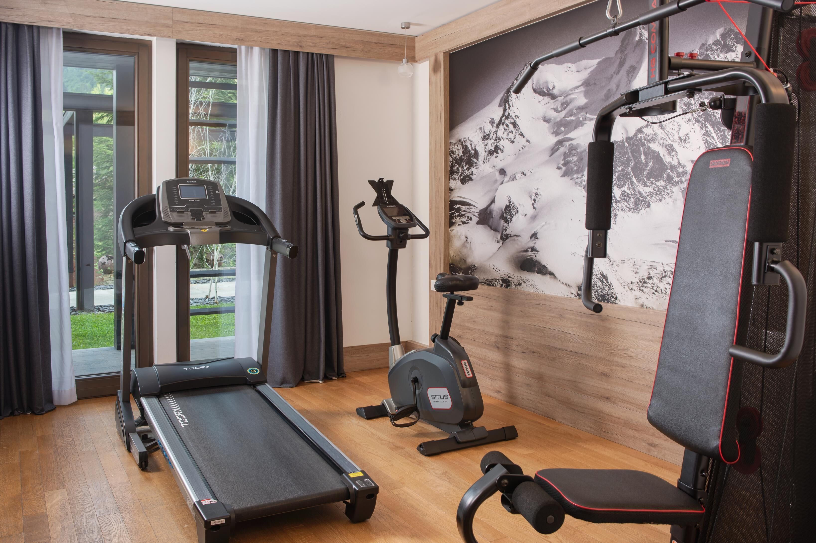 A home gym with a treadmill, stationary bike, and weight bench.