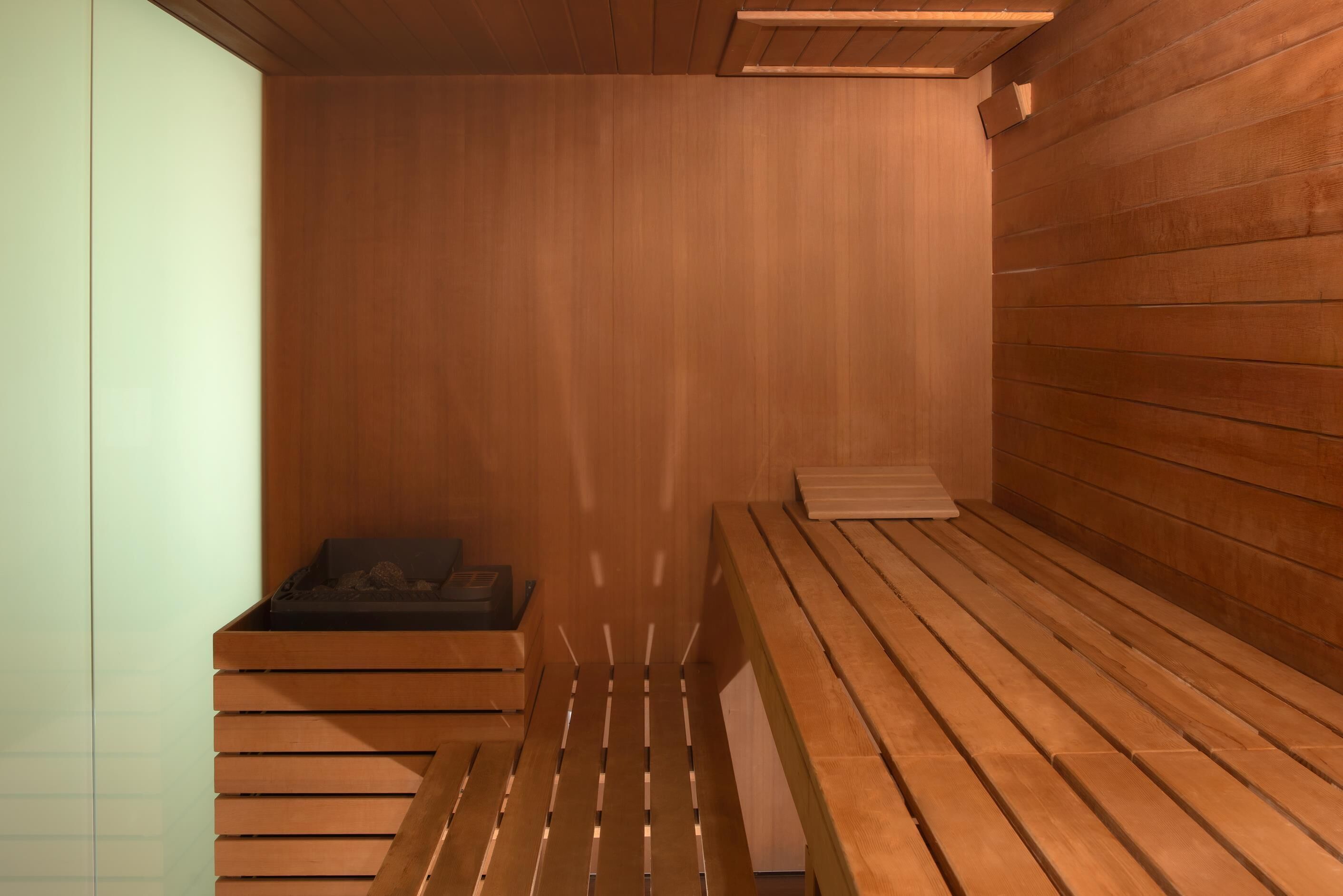 Eine Sauna mit Holzbänken und einer Bank mit schwarzem Sitzkissen.