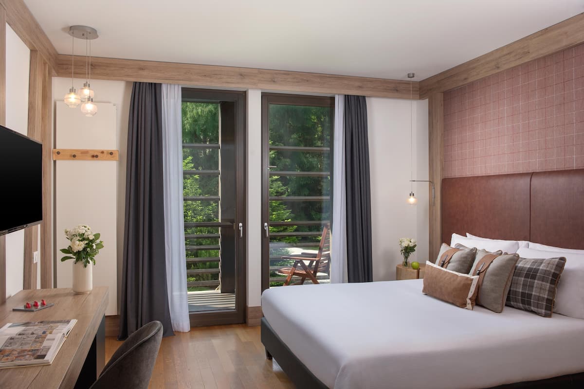 Een moderne slaapkamer met een groot bed, een houten bureau en een televisie.