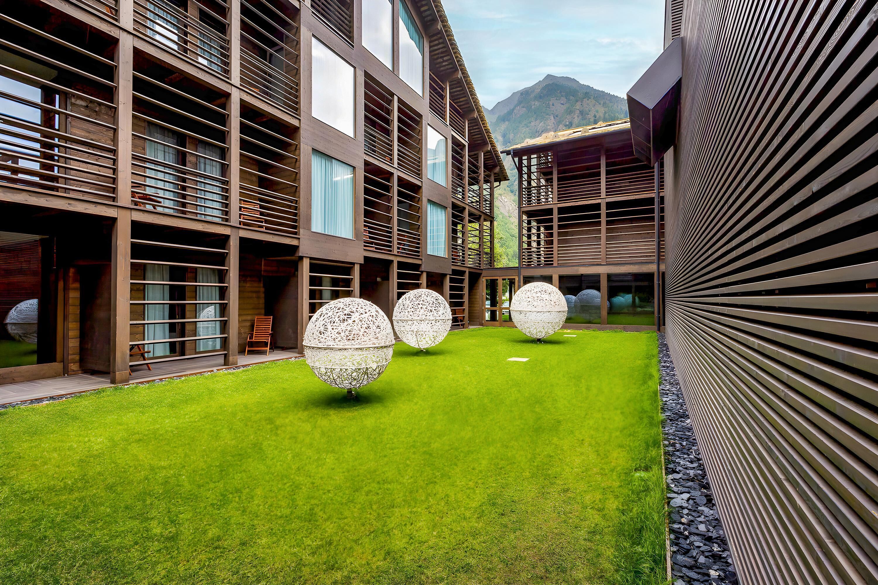 Un edificio moderno con un cortile interno, ampie finestre e vista sulle montagne.