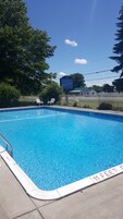 Una piscina al aire libre, sillones reclinables de piscina