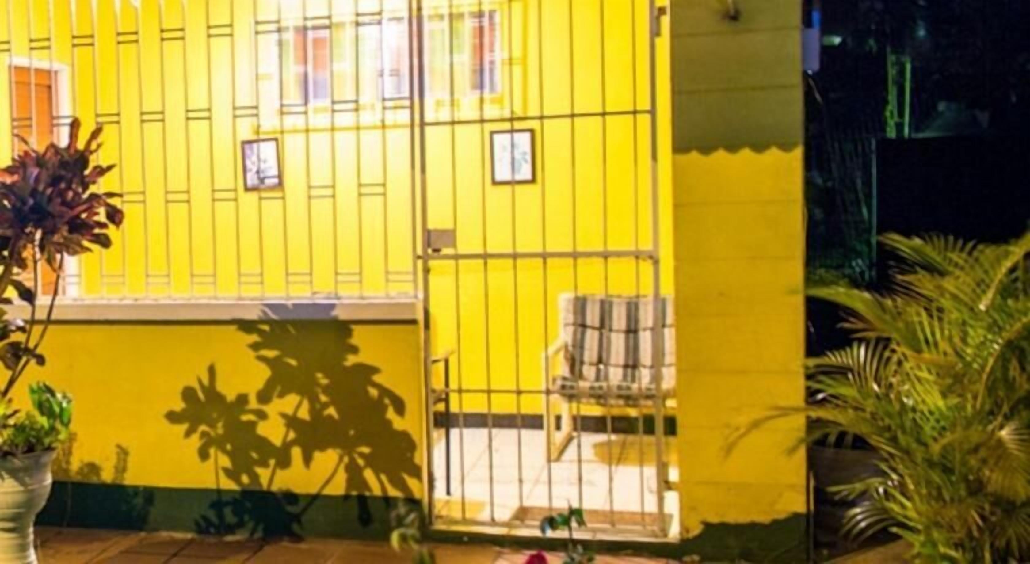 A yellow building with a balcony and a chair.