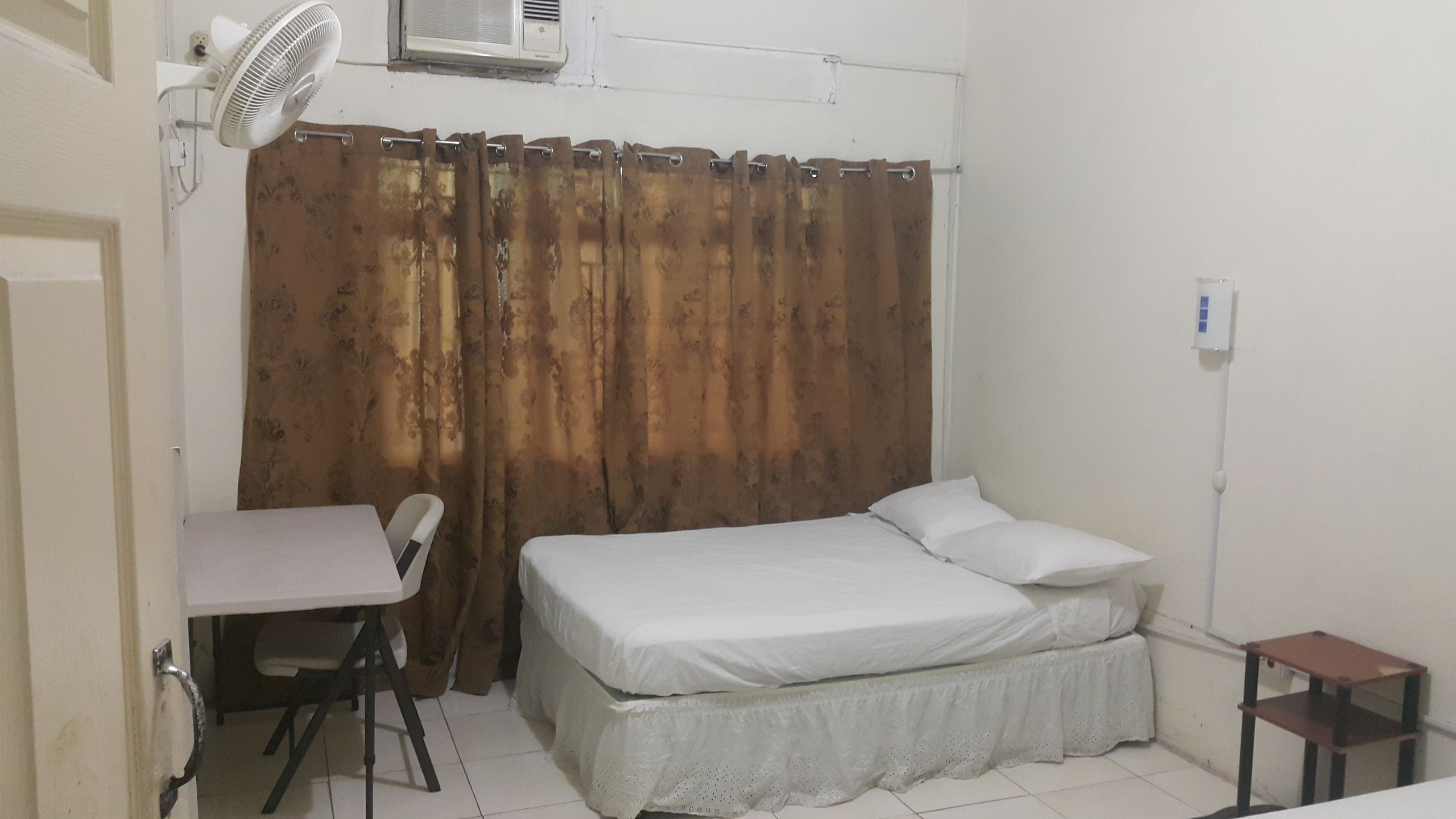 Una habitación pequeña y limpia con cama, escritorio y silla.