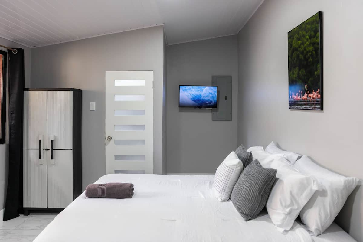 Ein Schlafzimmer mit einem Bett, einem an der Wand montierten Fernseher und einem Kleiderschrank.
