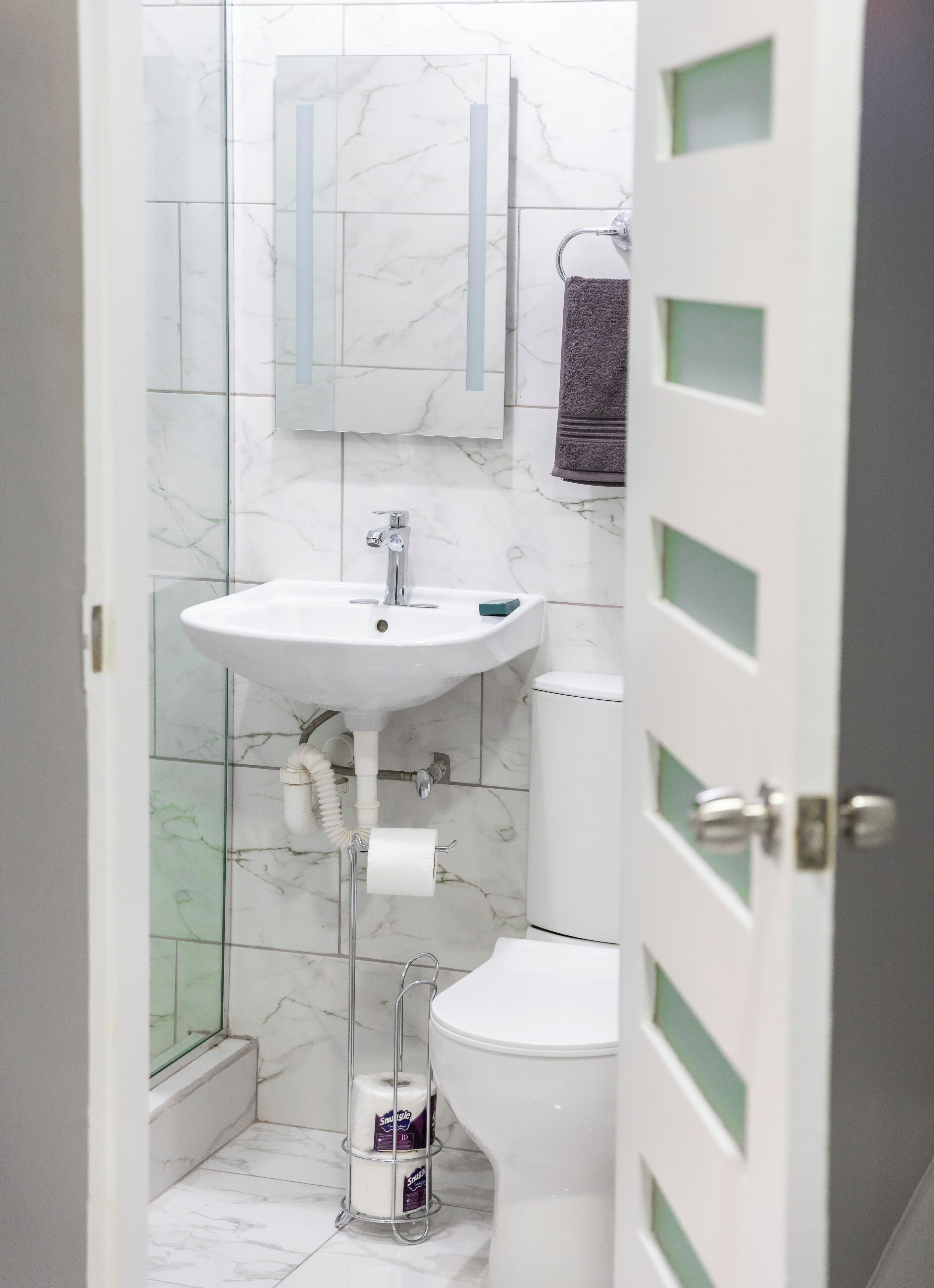 A bathroom with a white sink, a toilet, and a glass shower enclosure.