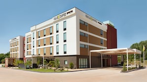 Ein modernes Hotel mit flachem Dach, mehreren Etagen und einem überdachten Eingangsbereich.