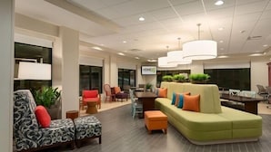 Eine moderne Lobby mit einem grünen Sofa, gemusterten Sessel und einem Essbereich.