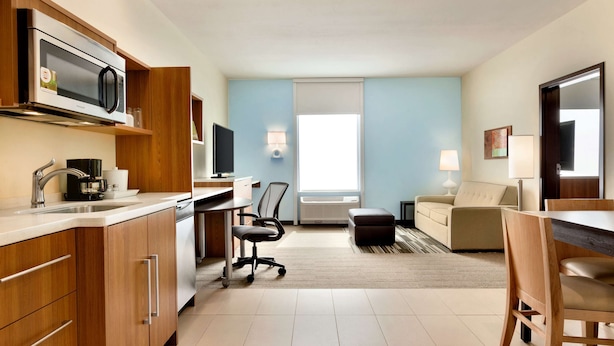 Ein modernes Hotelzimmer mit Küchenzeile, Essbereich, Sofa und Fernseher.