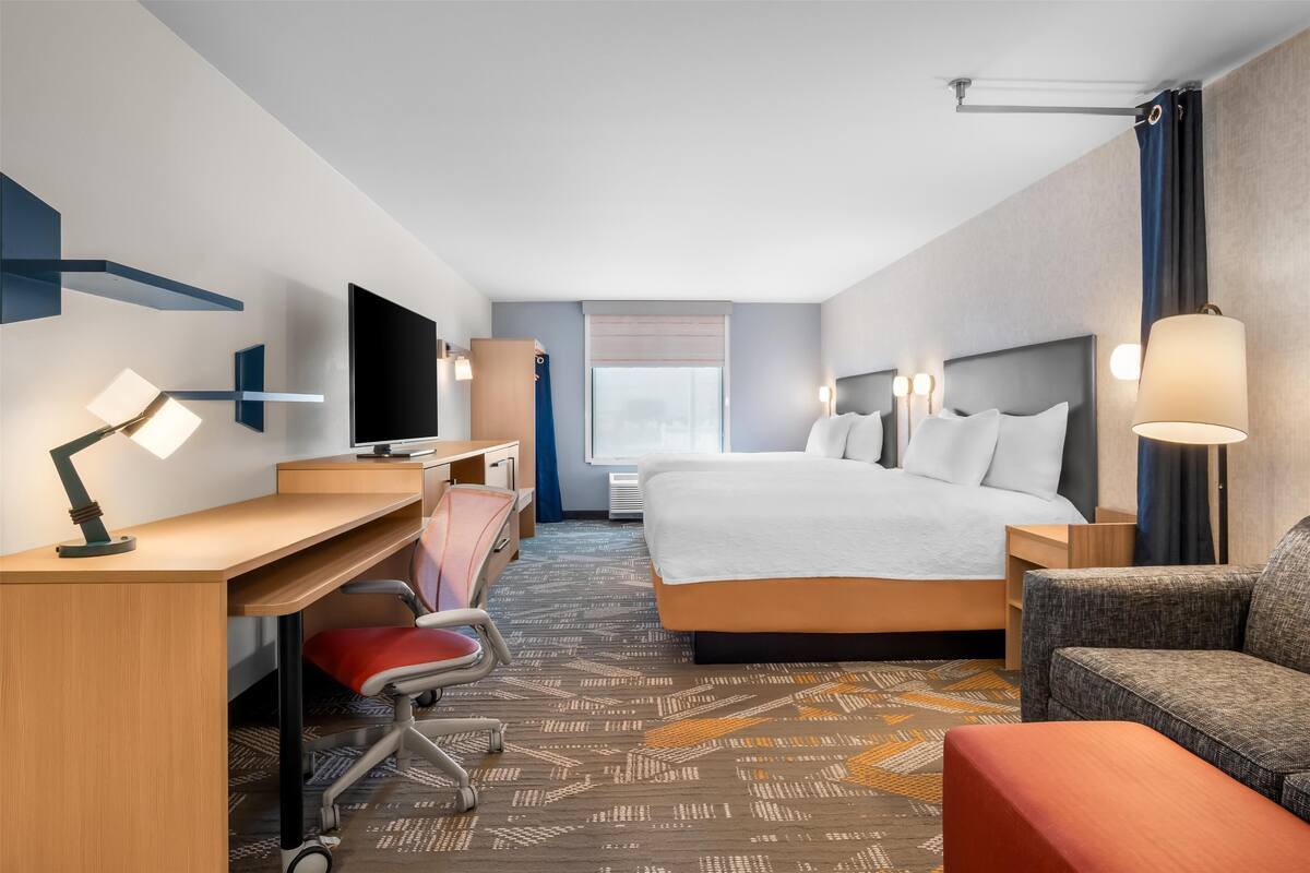 Een hotelkamer met een bed, bureau, stoel, televisie en een bank.