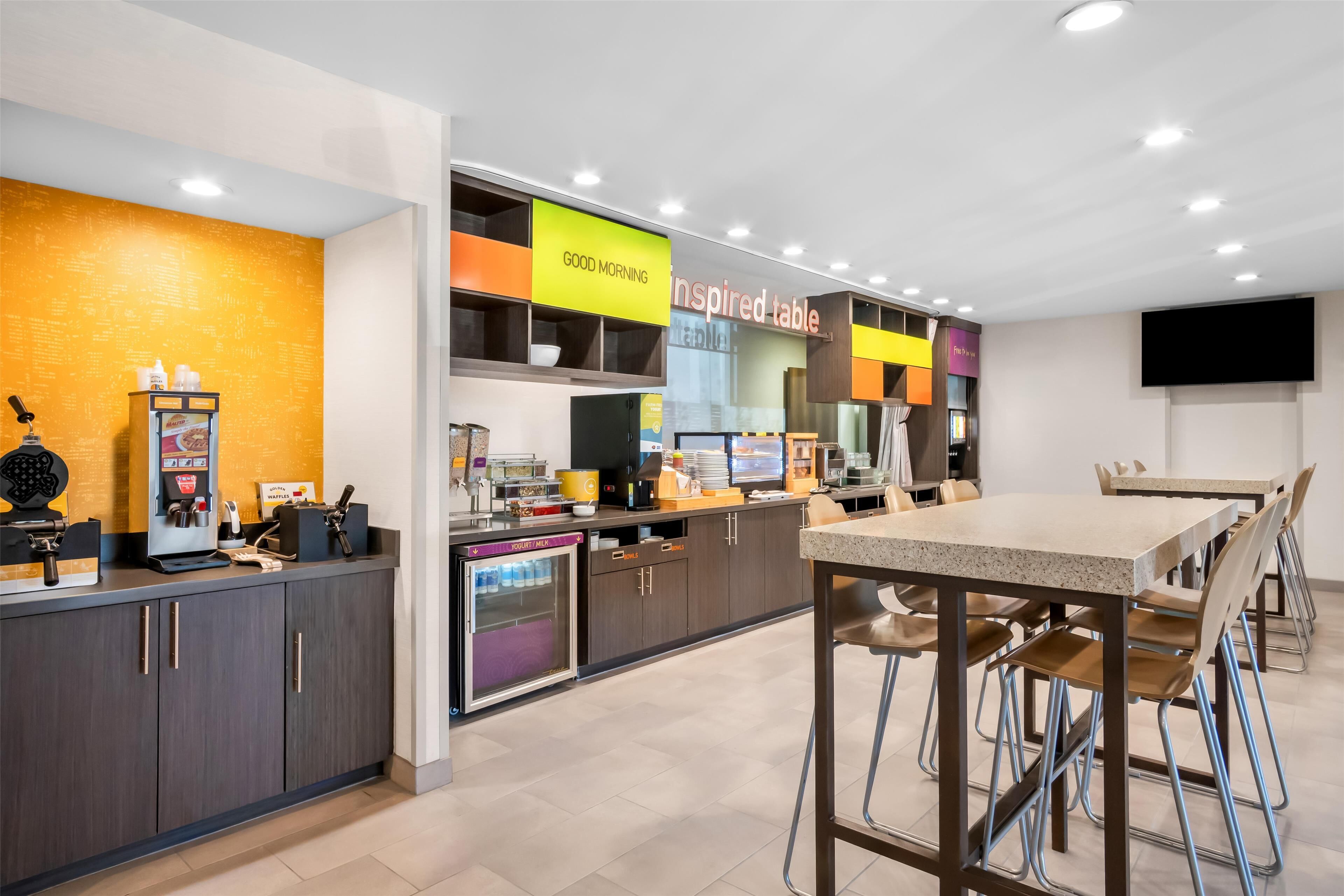 A modern café with a counter, seating area, and a sign that reads "GOOD MORNING Inspired table".