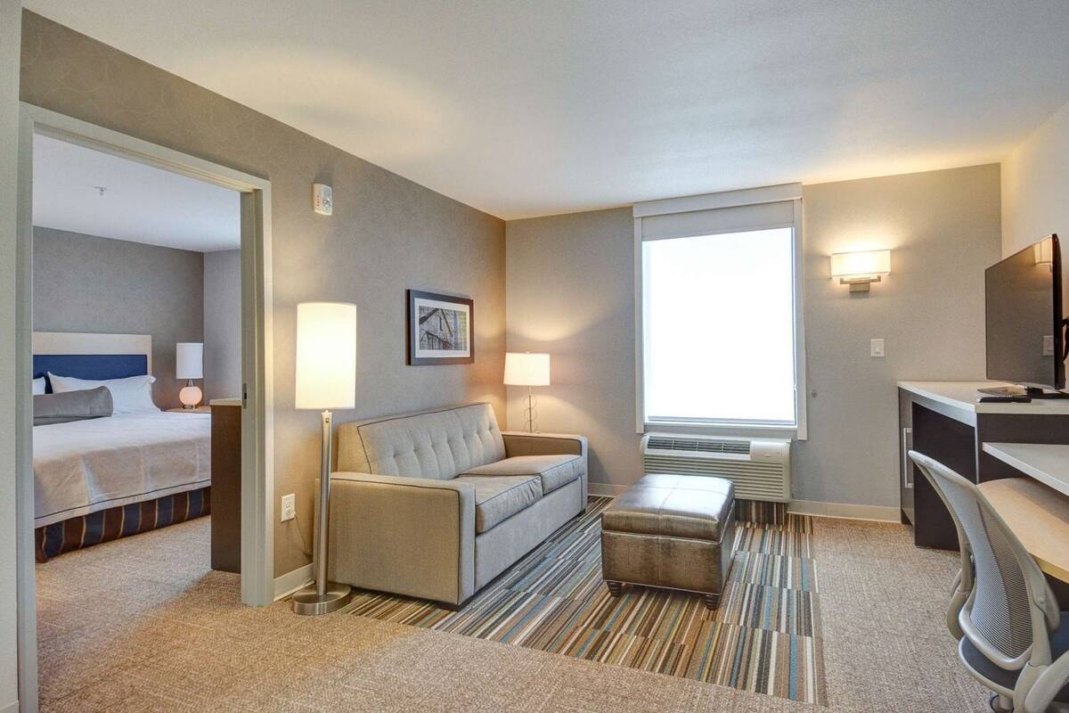 Een hotelkamer met een bed, een bank, een bureau en een groot raam.