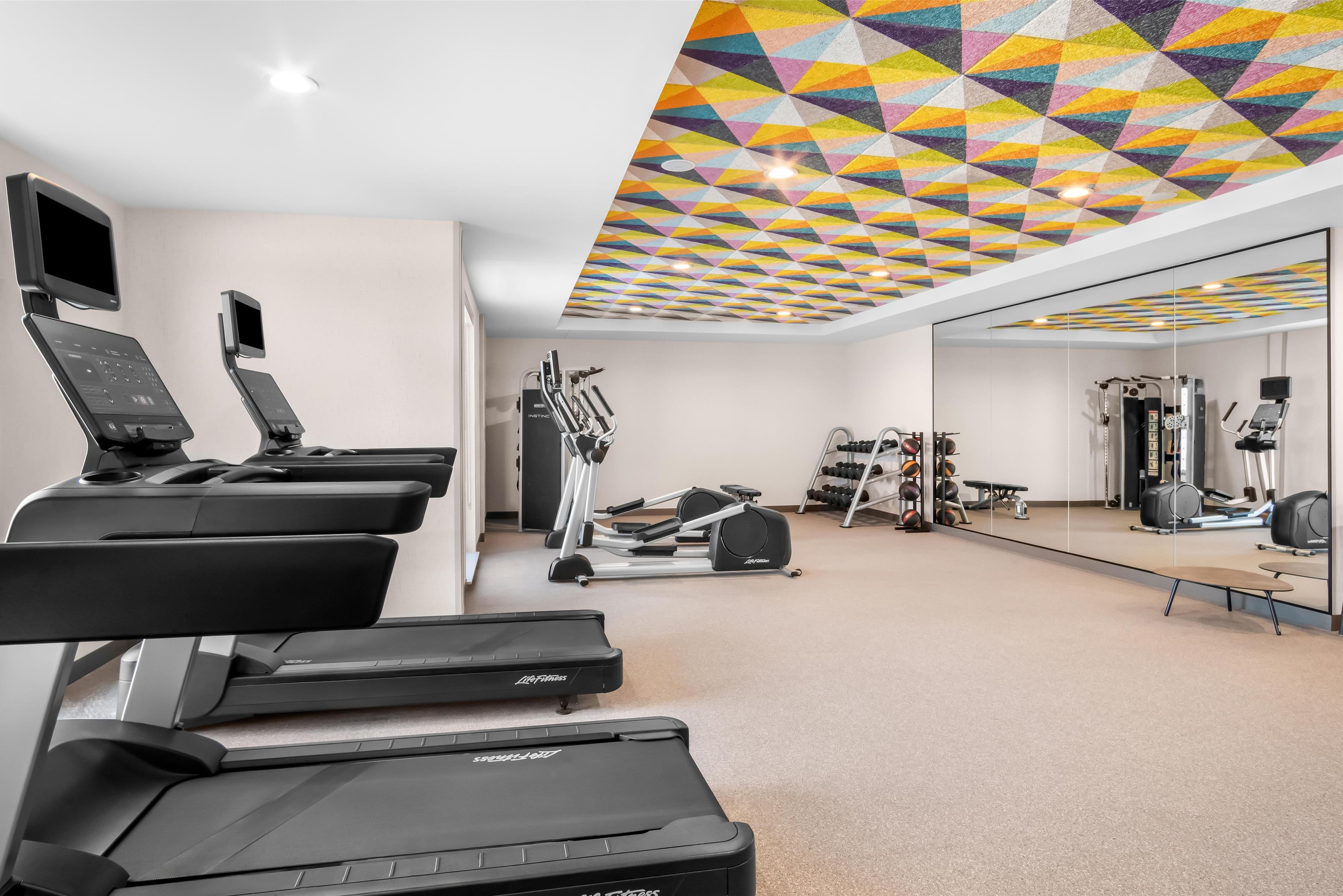 A gym with treadmills, elliptical machines, and free weights.