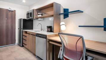 Cocina compacta con lavavajillas, microondas y cafetera en la encimera.