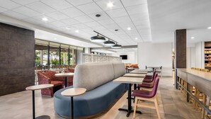 A modern restaurant interior with a blue seating area, round tables, and a bar counter. - Home2 Suites by Hilton Irving / DFW Airport North (Irving)