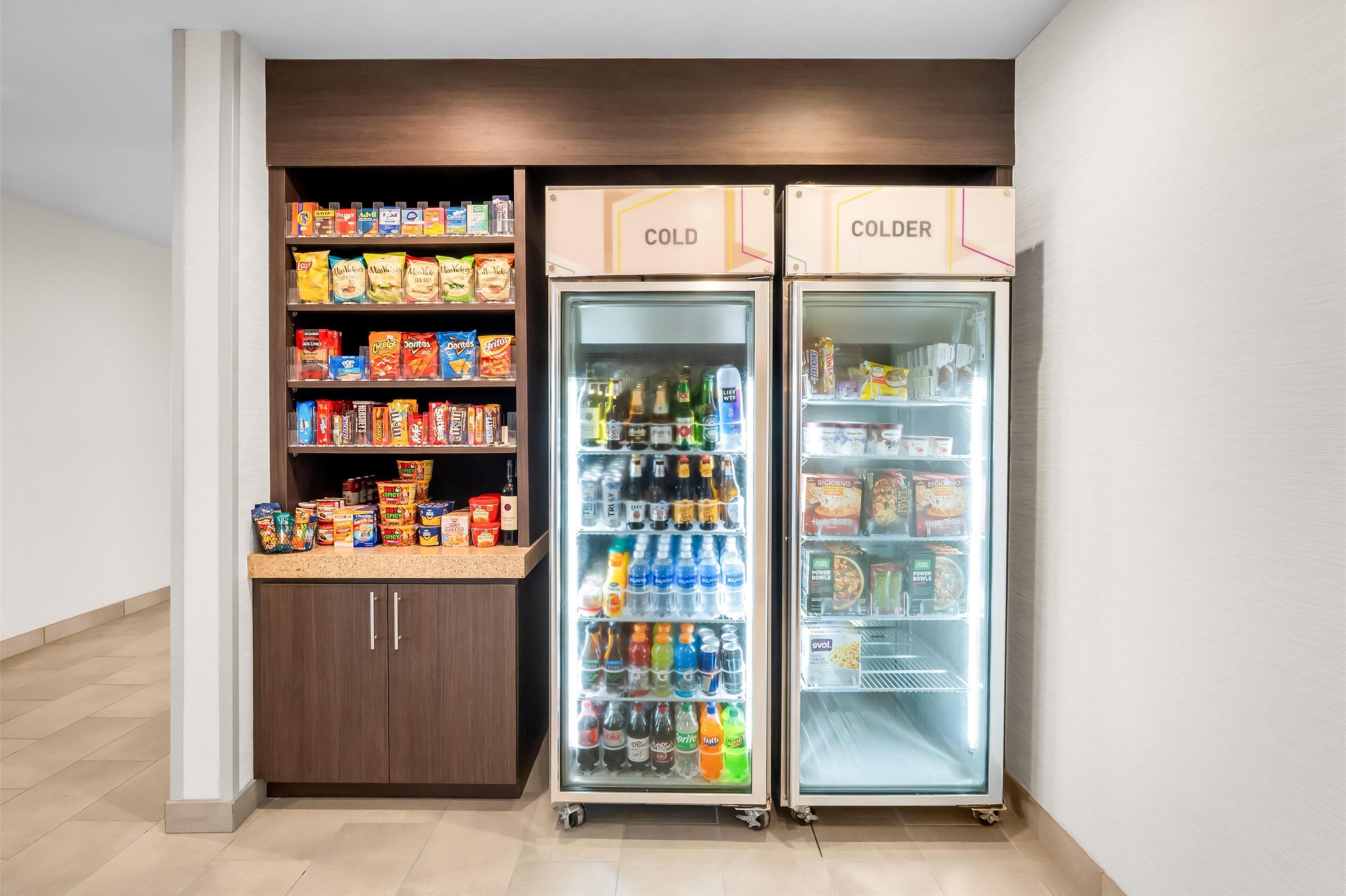 Una kitchenette equipada con refrigerador y congelador, con provisiones de bocadillos y bebidas.