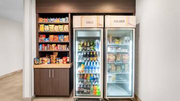 Una kitchenette equipada con refrigerador y congelador, con provisiones de bocadillos y bebidas.