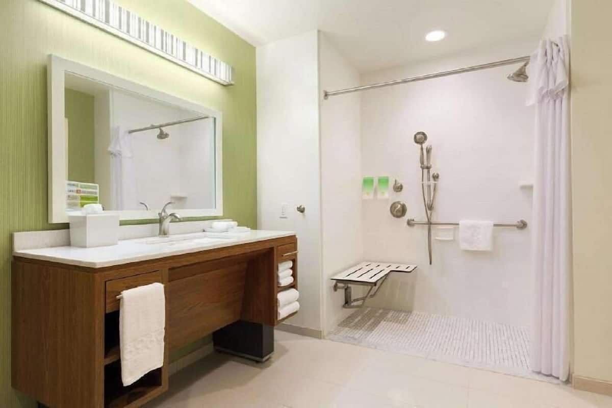 A bathroom with a wooden vanity, a large mirror, a shower with a glass door, and a towel rack.