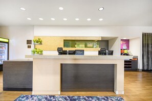 A hotel reception desk with a 'HOME2' sign, a 'Hilton Honors' plaque, and a coffee machine. - Home2 Suites by Hilton Albany Wolf Rd (Albany)