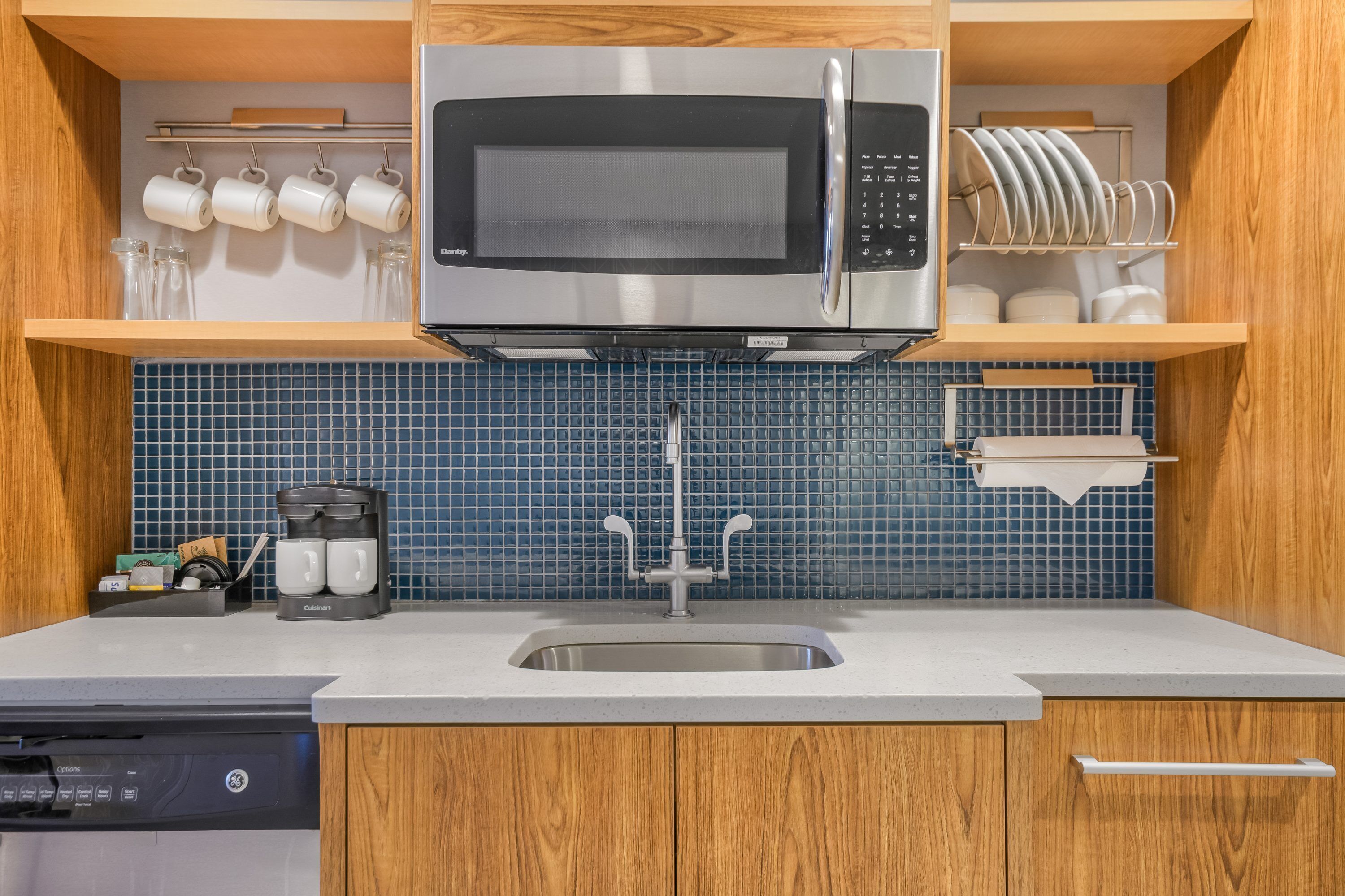A kitchen with a built-in microwave, a coffee maker, and a dish rack.