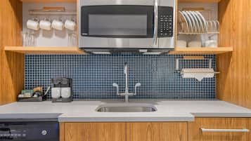 A kitchen with a built-in microwave, a coffee maker, and a dish rack.