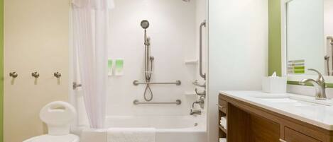 A bathroom with a bathtub, shower, and a vanity with a sink.
