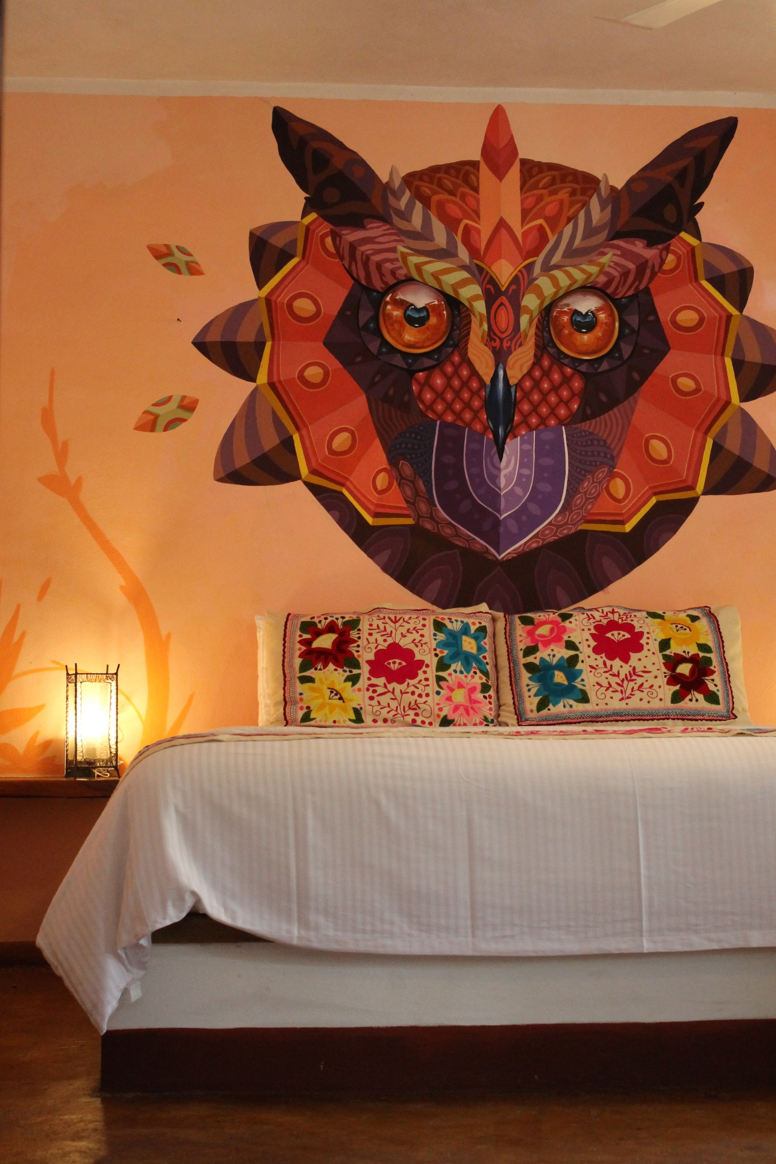 A bed with a white bedspread and two pillows with colorful floral patterns.