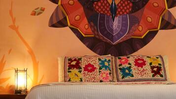 A bed with a white bedspread and two pillows with colorful floral patterns.