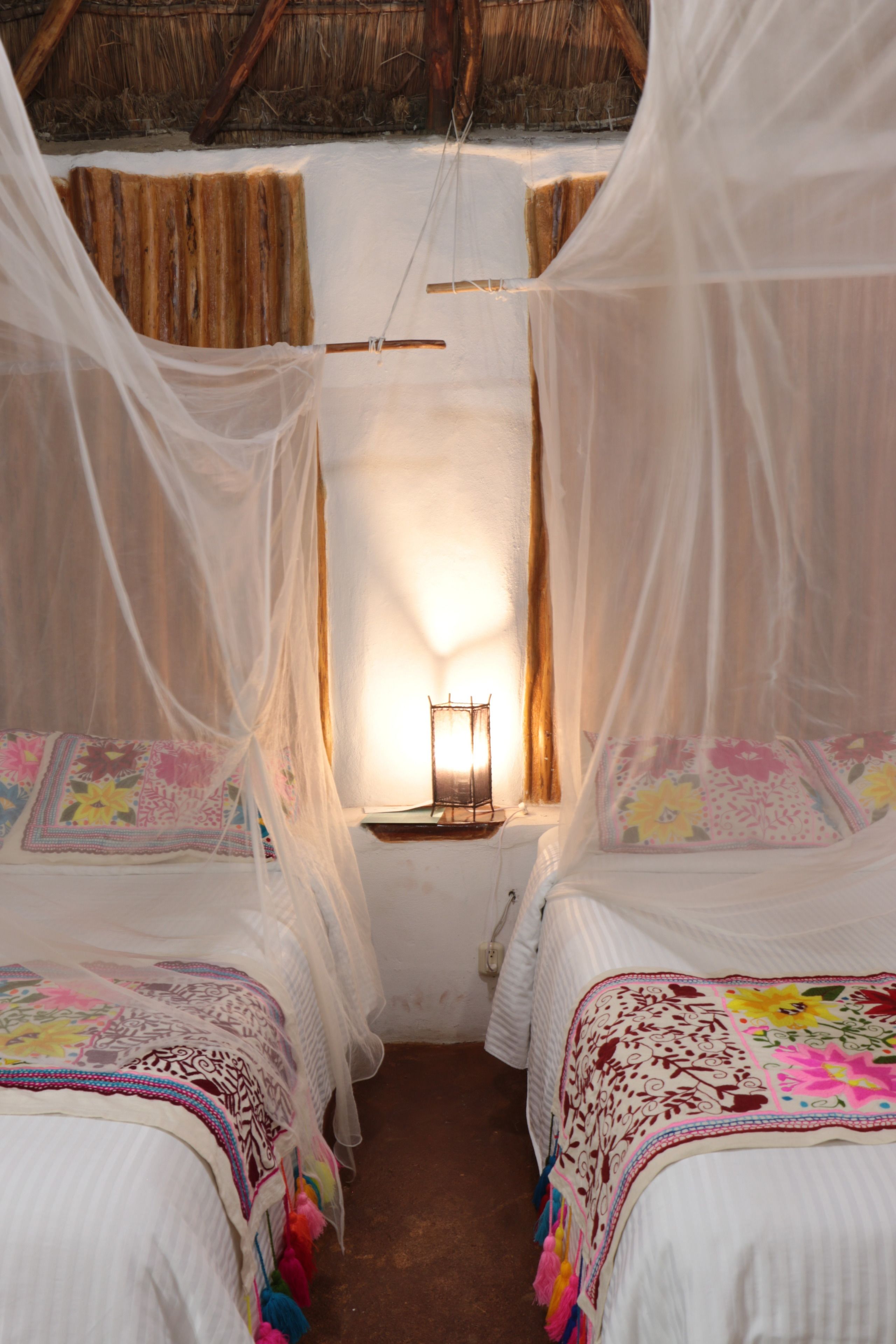 Una habitación con dos camas, cada una cubierta por un dosel y ropa de cama floral.