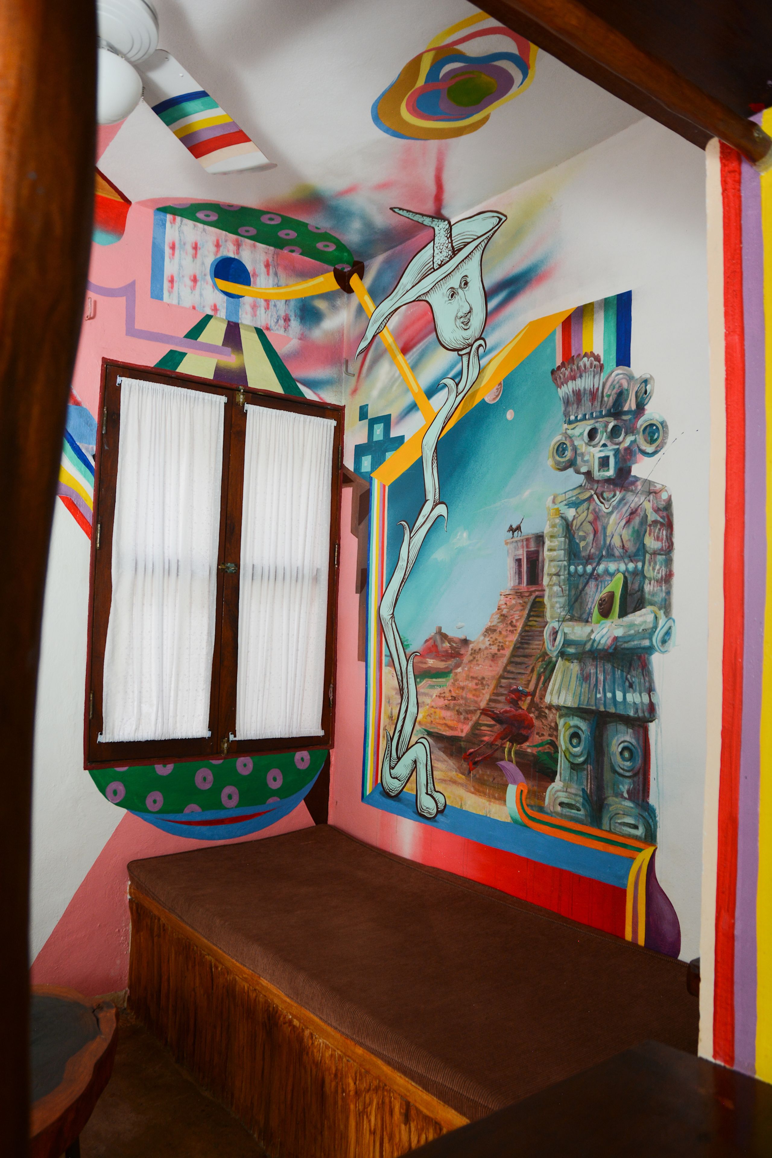 A room with a mural, a window with curtains, and a bed.