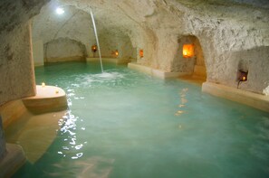 Un interior que recuerda a una cueva, con una piscina e iluminación cálida.