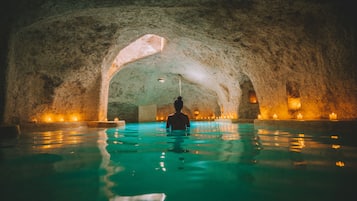 Relax in a serene, cave-like setting with a tranquil indoor pool surrounded by natural rock formations.