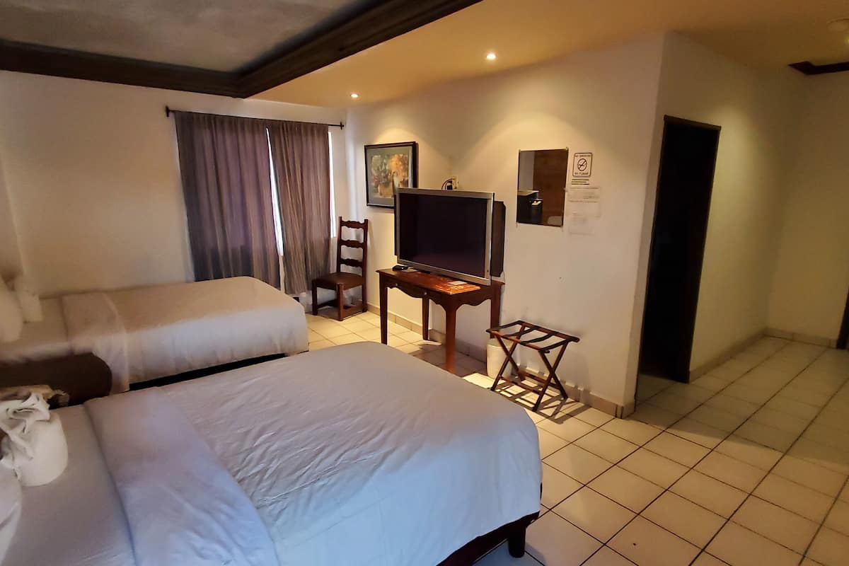 A hotel room with two beds, a television, a small table, and a chair.