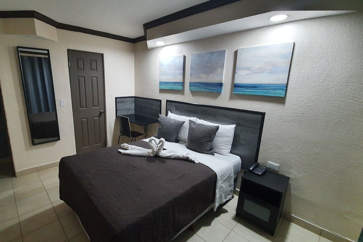 A hotel room with a large bed, a desk, and a phone on the side table.
