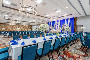 A banquet hall with rows of tables, blue chairs, and floral centerpieces. - Hilton Garden Inn Bolingbrook I-55 (Bolingbrook)