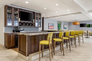 Zona de bar con televisor de pantalla plana, enfriador de vino y minibar.