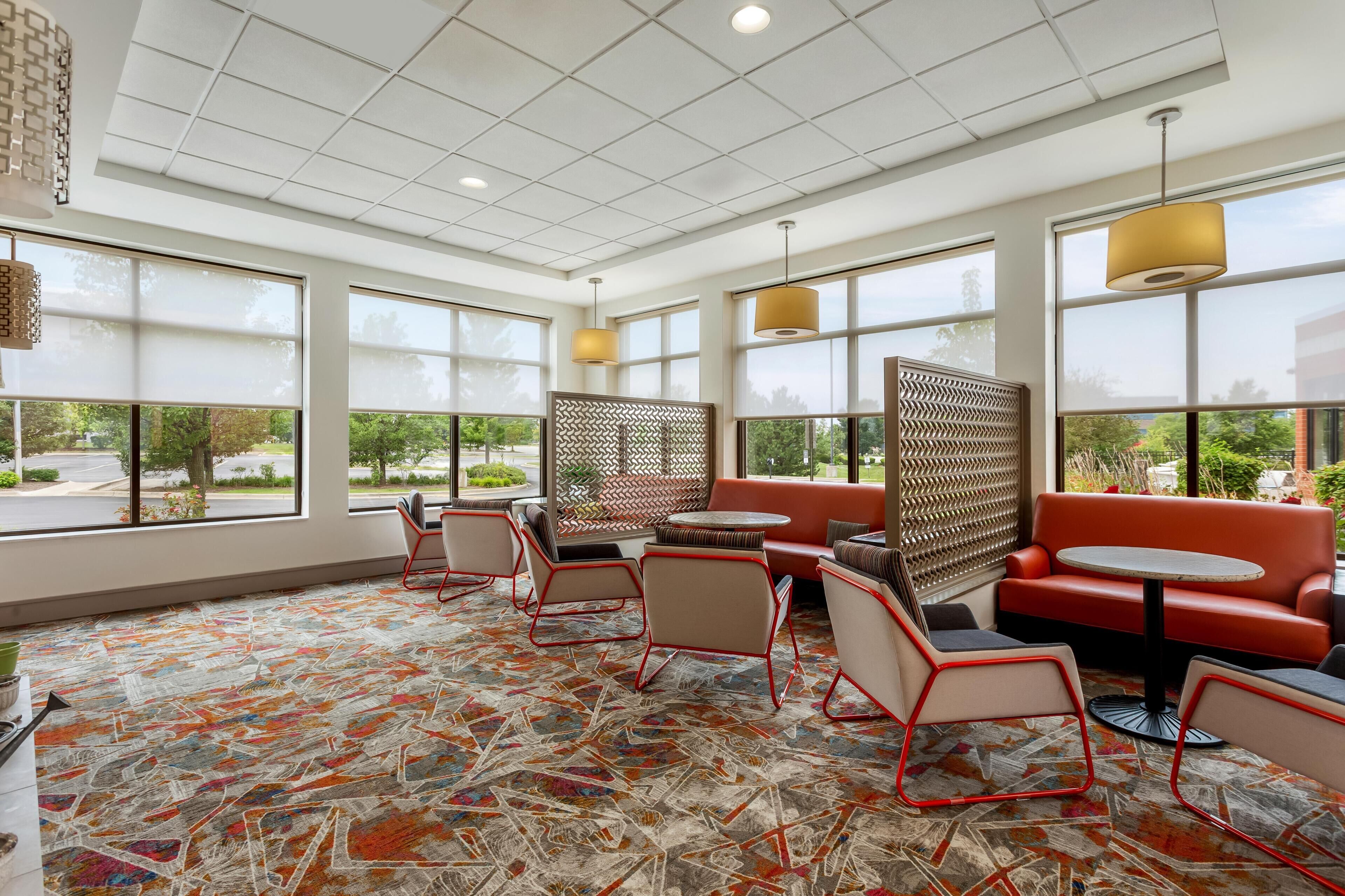 A modern interior with a patterned carpet, seating area, and large windows.