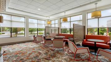A modern interior with a patterned carpet, seating area, and large windows.