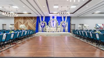 Une salle de conférence dotée d’une scène, de chaises bleues et d’un tapis à motifs.