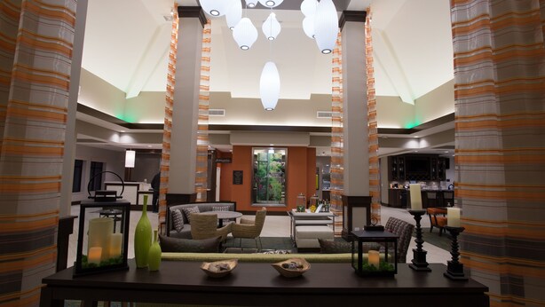 A spacious lobby with a central seating area, a dining table with candles, and a modern chandelier. - Hilton Garden Inn Bolingbrook I-55 (Bolingbrook)