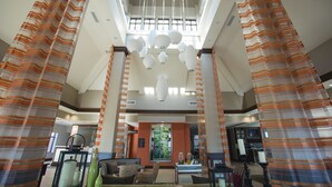 A spacious lobby with a high ceiling, striped curtains, and a central chandelier. - Hilton Garden Inn Bolingbrook I-55 (Bolingbrook)