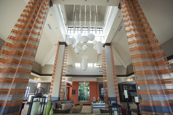 A spacious lobby with a high ceiling, striped curtains, and a central chandelier. - Hilton Garden Inn Bolingbrook I-55 (Bolingbrook)