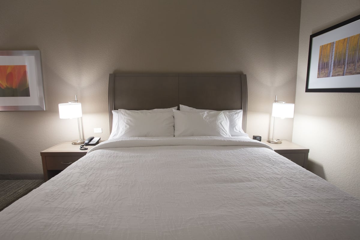 A hotel room with a large bed, two bedside tables with lamps, and framed artwork on the walls.