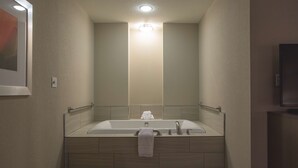 A modern bathroom with a freestanding bathtub, a handrail, and a towel rack. - Hilton Garden Inn Bolingbrook I-55 (Bolingbrook)
