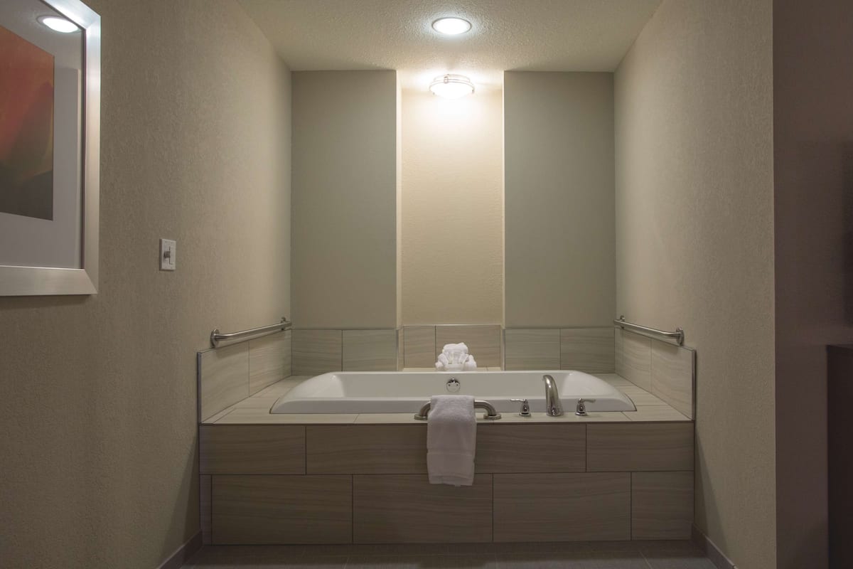 A modern bathroom with a freestanding bathtub, a handrail, and a towel rack.