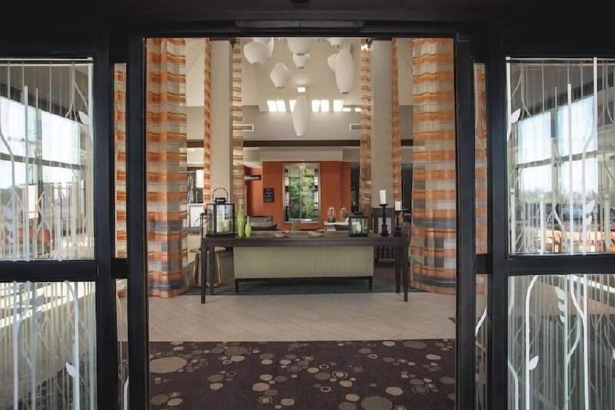 A hotel lobby with a reception desk, patterned curtains, and a modern ceiling design.