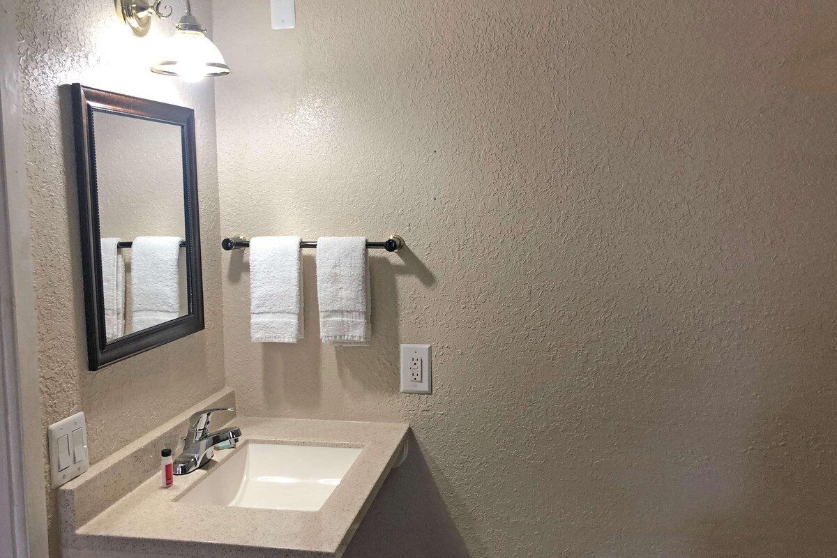 A bathroom with a sink, mirror, towel rack, and wall-mounted light fixture.