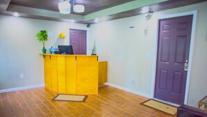 A reception area with a wooden desk, a potted plant, and a purple door.